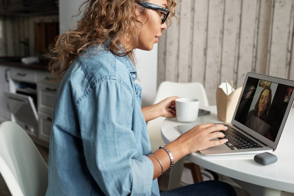 Woman in Blue Denim Jacket Using Macbook Pro for a video call